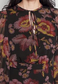 Mustat kukalliset mekko pitkine läpinäkyvine hihoineen. Ominaisuus pyöreä kaula-aukko avauksella, koristeltu punaisilla, vaaleanpunaisilla ja keltaisilla kukkakuoseilla.