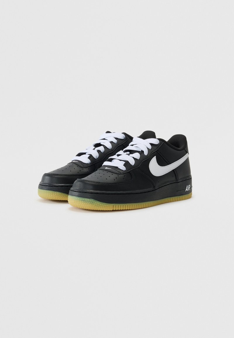 Schwarze Leder-Sneaker mit weißen Schnürsenkeln, perforierter Zehenbox und einem grauen Nike-Logo. Verfügt über eine Gummisohle mit grünlichem Farbton.