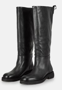 Botas de cuero negro hasta la rodilla con una textura suave, punta redondeada, tacón bajo y un diseño de costuras. Presentan una lengüeta en la parte posterior.