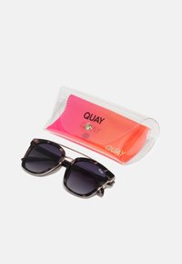 Slnečné okuliare s tmavým gradientovým sklom a rámom v štýle korytnačky, spolu s priehľadným farebným puzdrom a ružovou mikrovláknovou utierkou.