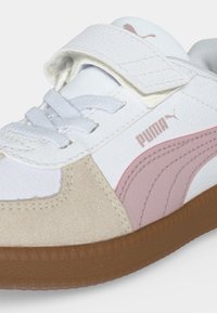Λευκό και μπεζ αθλητικό παπούτσι Puma με ροζ πλαϊνή λωρίδα, καφέ σόλα, λευκά κορδόνια και κλείσιμο με βέλκρο.