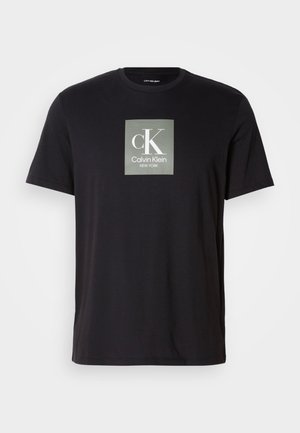 Must mustaga t-särk lühikeste varrukatega, millel on hall ruudukujuline logo, kus on keskel suur "cK" ja "Calvin Klein NEW YORK" tekst rinnal.