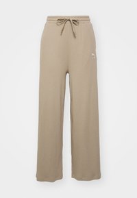 Pantaloni de sudură bej, cu model în dungi, cu talie ajustabilă și fante laterale; prezintă un logo brodat pe coapsă. Textură moale, croi lejer.