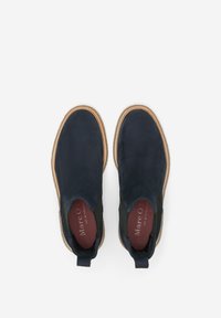 Zapatos de ante azul marino sin cordones, con paneles laterales elásticos, suelas de goma beige y un interior con marca roja.