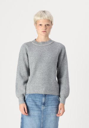 Pull gris côtelé à manches longues, décolleté arrondi orné d'accents métalliques. Assorti à une jupe en denim claire.