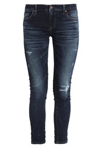 Jeans ajustados de mezclilla azul oscuro, con parches desgastados, detalles destruidos, cinco bolsillos, cierre de cremallera y un silueta entallada.