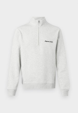 Svetlo šedý sveter s polovičným zipsom a na prednej strane vyšitým nápisom "Original Studio" v čiernej farbe, zobrazený na bielom pozadí.