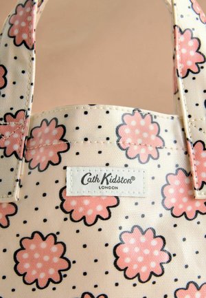 Sac fourre-tout floral mettant en vedette des fleurs roses avec des contours noirs sur un fond crème, des accents à pois, et une étiquette brodée avec "Cath Kidston".