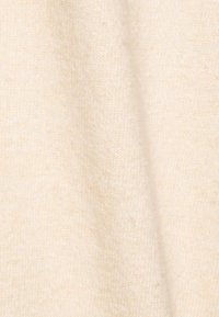 Tejido de punto básico en un color beige claro, con una textura suave y un brillo sutil, que muestra ligeras variaciones en tono y densidad.