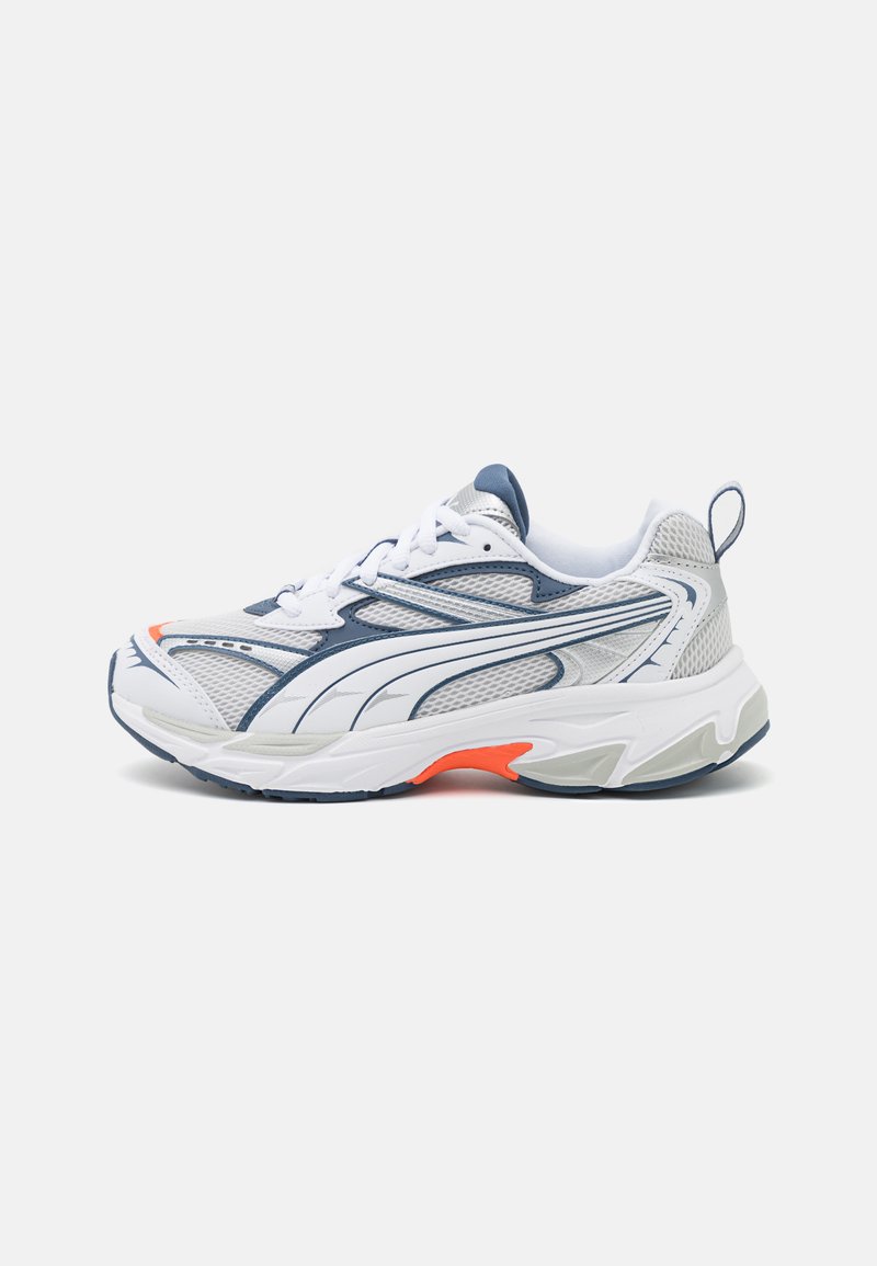 Scarpa atletica bianca con accenti blu navy e arancioni, tomaia in rete, sovrapposizioni testurizzate, suola in gomma e lacci. Presenta un linguetta posteriore.