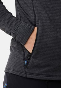 Schwarzer technischer Pullover aus strukturiertem Gewebe mit Reißverschlusstaschen, die blaue und gelbe Akzente aufweisen, sowie enganliegende Bündchen.