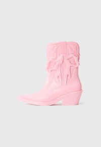 Cizmul de cowboy din plastic roz, cu vârful ascuțit și toc masiv. Prezintă un detaliu cu fundiță ridicată pe lateral și marcaj gravat. Textură netedă.
