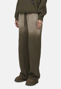 Olive zielone oversize'owe spodnie dresowe z efektem gradientu. Wykonane z miękkiego materiału, z elastycznym paskiem w talii i szerokimi nogawkami.