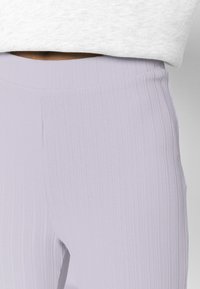 Ljus lavendelribbad leggings med hög midja och en smidig textur, designade för en åtsittande look med subtila sömdetaljer.