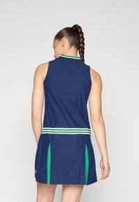 Vestido de ténis azul-marinho com design sem mangas, apresentando destaques em verde e branco nas golas e na cintura, além de pregas laterais.
