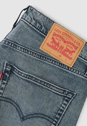 Levi's Jeans aus Denim mit ausgewaschenem Blauton, Lederetikett mit rotem Grafikdruck und klassischer Bogenstickerei auf den Gesäßtaschen.