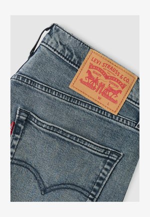 Levi's Jeans aus Denim mit ausgewaschenem Blauton, Lederetikett mit rotem Grafikdruck und klassischer Bogenstickerei auf den Gesäßtaschen.