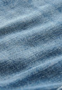 Denim tkanina u svijetloplavoj boji, koja prikazuje teksturirani, tkanu uzorak s vidljivim dijagonalnim linijama i mekanim, lagano rastegnutim izgledom.