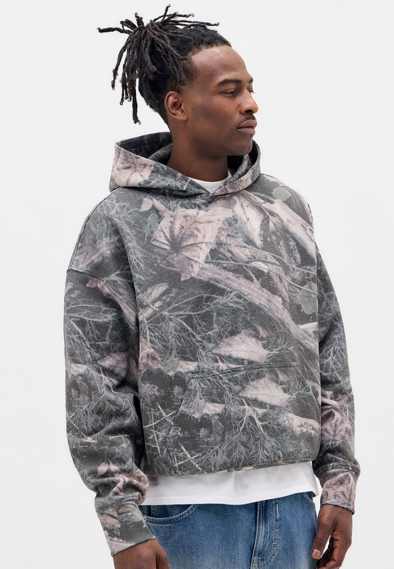 Hættetrøje med camouflage-design, der har grå, grønne og lyserøde bladmønstre. Blødt stof med løs pasform og foran lomme.