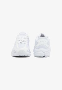 Chaussures de sport blanches avec une tige en mesh et synthétique, des semelles texturées, et un marquage sur le côté et à l'arrière pour un design épuré et moderne.
