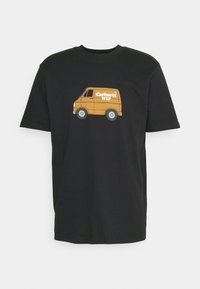 Camiseta negra de manga corta con un gráfico de una furgoneta de entrega marrón y el texto blanco "Carhartt WIP" en el centro del frente.