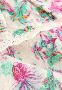 Tessuto di cotone floreale con motivi rosa, verdi e blu. Presenta un delicato bordo di pizzo lungo il bordo, che aggiunge texture e dettaglio.