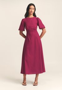 Fuksia midi-mekko puffihihnoilla, kapealla vyötäröllä ja sileällä pinnalla. Ominaisuuksiin kuuluu yksinkertainen pyöreä pääntie ja virtaava hame.