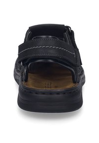 Black sandal with adjustable straps, textured upper material, cushioned insole, and a solid rubber sole. Features contrast stitching details.