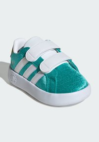 Tyrkysové tenisky s lesklou textúrou, biele suché zipsy a tri biele pruhy. Zaoblená špička a biela podrážka s vzorovaným akcentom.