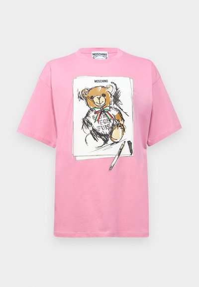 Pink cotton t-shirt featuring an illustrated teddy bear with a bow, surrounded by sketch-like lines and a pen detail.