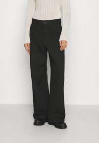Zwarte wijde pantalons van stevige stof, voorzien van een knoopsluiting en zakken, gecombineerd met een geribbelde lange mouw top.