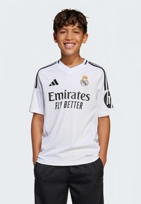 Valge Adidas jalgpallipluus mustade detailidega, millel on kiri „Emirates Fly Better“, klubi vapp ja V-kaelusega disain.