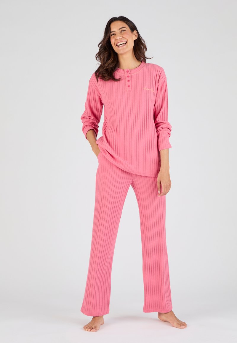 Conjunto de loungewear de color rosa con textura acanalada, que incluye mangas largas y un escote abotonado, combinado con pantalones de pierna recta. Textura suave y ajuste relajado.