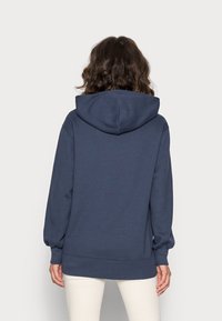 Granatowa bluza z dużym kapturem, ściągaczami przy rękawach i u dołu. Wykonana z miękkiego materiału, charakteryzująca się luźnym krojem i minimalistycznym designem.