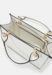 White leather handbag with black trim, gold hardware, and interior zippered compartment, featuring embossed brand logo on the exterior.