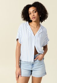 Blå och vitrandig skjorta med knappar, krage, korta ärmar och löst snitt, tillsammans med ljusa denimshorts.