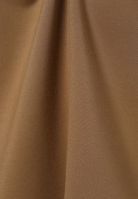 Tissu doux et texturé dans une teinte brune chaude, présentant un drapé lisse et un léger éclat, adapté pour les vêtements ou la tapisserie.