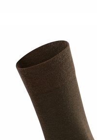 Chaussette en laine marron avec une texture côtelée au niveau du revers, se rétrécissant vers un corps lisse. Le matériau semble doux et flexible.