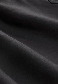 Schwarzer Stoff mit glatter, strukturierter Oberfläche, dezentem Glanz und diagonalen Webmustern, dargestellt in sanften Falten.