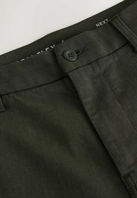 Dunkelgrüne Hose mit glatter Textur, ausgestattet mit einem Knopfverschluss, Gürtelschlaufen und gestickten Details am Taillenbund.
