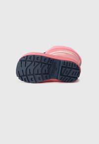 Suela de bota en rosa y navy exhibida, mostrando suelas y detalles texturizados, diseñados para agarre y estabilidad.