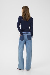Navy ribbed sweater with long sleeves paired with wide-leg light blue denim jeans featuring two back pockets in contrasting fabric.