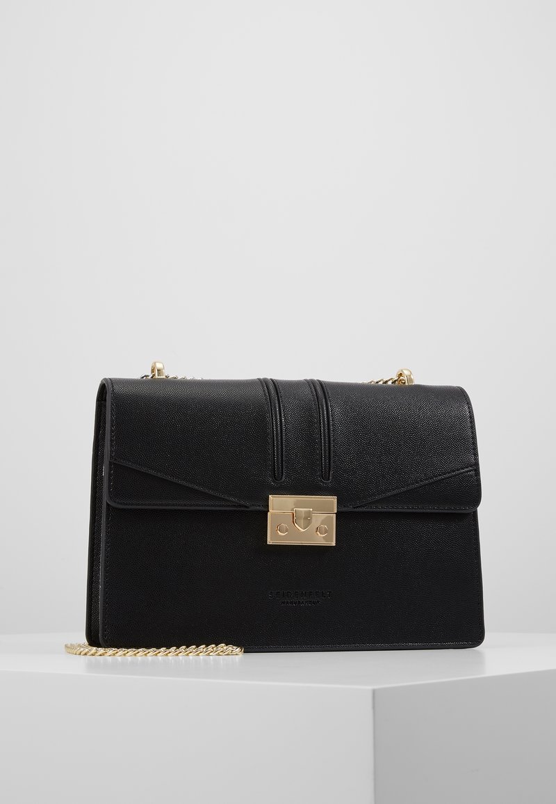Borsa a tracolla in pelle nera con design strutturato, chiusura in metallo dorato e tracolla a catena. Presenta cuciture verticali sul cappuccio e logo impresso.