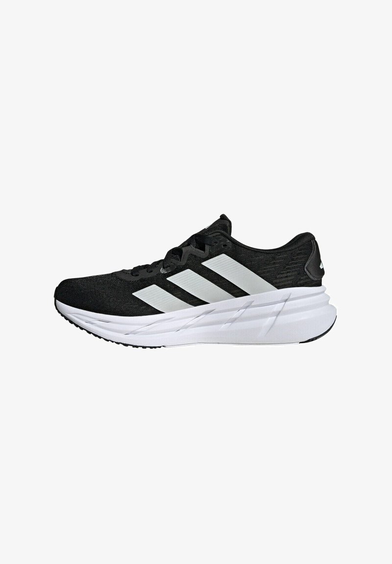 Chaussures de sport noires avec une tige en tissu texturé, dotées de trois bandes blanches, d'une semelle blanche rembourrée et d'une semelle extérieure noire pour une meilleure adhérence.
