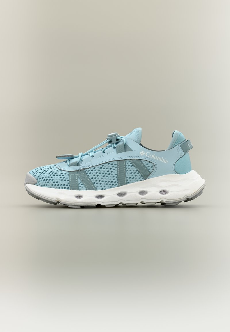 Ανοιχτό μπλε αθλητικό παπούτσι Columbia με διαπνέον πλέγμα, λευκή μαξιλαρωτή σόλα και ρυθμιζόμενο κορδόνι με κουμπί σε ουδέτερο φόντο.