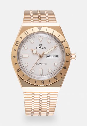 Orologio da polso al quarzo con quadrante rotondo bianco, cassa e lunetta color oro. Presenta un bracciale in maglia di acciaio inossidabile e display della data.