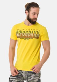 Gele crewneck t-shirt van katoen met een grafische print met de tekst "NY CITY STREET STYLE" in vetgedrukte zwarte en bruine tinten.