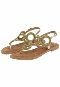 Sandali in tonalità oro, impreziositi da design circolari, con punta a un dito e una cinturino alla caviglia regolabile. La suola è di un marrone chiaro con una finitura scamosciata.