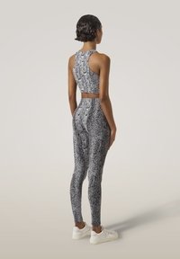 Zwart-wit slangenprint sportoutfit met een cropped top met racerback en high-waisted leggings, gemaakt van rekbaar materiaal.