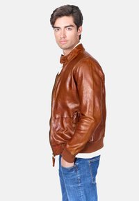 Bruine leren bomberjack met een ritssluiting, geribbelde manchetten en onderkant, zijzakken en een gladde, glanzende textuur.